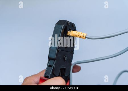 Specialist crimps connector on network cable using crimper Stock Photo