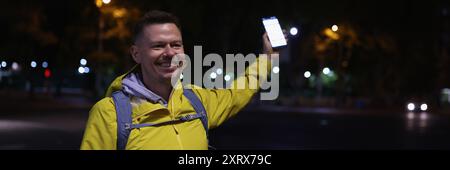 Man in yellow coat holding mobile phone in hand Stock Photo