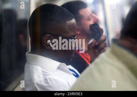 A man uses a fan whilst on the Piccadilly Line, London. The UK has seen its hottest day of the year so far after a temperature of 34.8C was recorded in Cambridge, the Met Office has said. Picture date: Monday August 12, 2024. Stock Photo