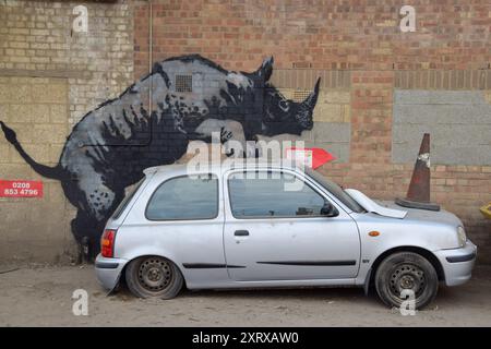 London, UK. 12th Aug, 2024. A new artwork by Banksy appears on a wall in Charlton, depicting a rhino getting intimate with a car with a traffic cone on its hood. This is the 8th new animal-themed artwork in eight days in the capital by the elusive street artist. (Photo by Vuk Valcic/SOPA Images/Sipa USA) Credit: Sipa USA/Alamy Live News Stock Photo