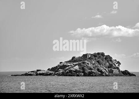 Rocky islet with historic buildings on the Cyclops coast in Sicily, Italy,  monochrome Stock Photo