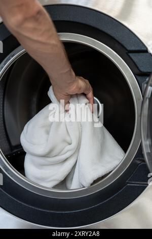 Unrecognizable man operating using washing machine at commercial laundry Stock Photo