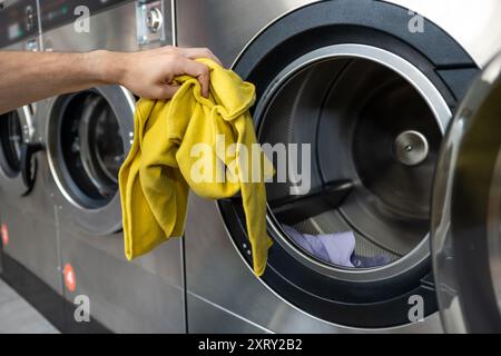 Unrecognizable man operating using washing machine at commercial laundry Stock Photo