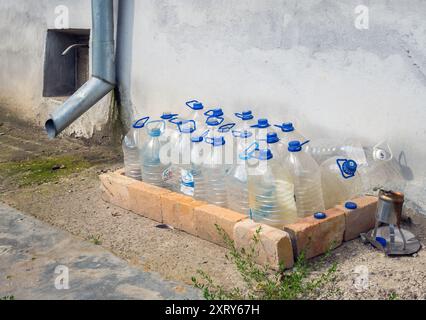 Voronezh, Russia - August 02, 2023: Empty plastic bottles for collecting rainwater stand next to a drain Stock Photo