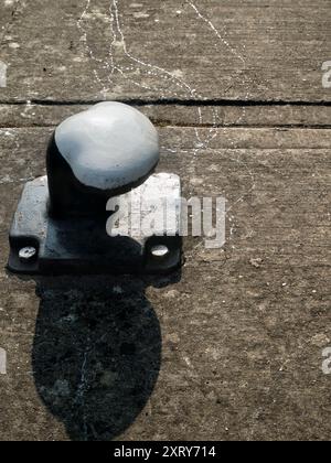 Mooring post and slug tracks by the Thames. Close-up of mooring post by Abingdon lock gates on a fine summer morning; these scenic locks are on the River Thames just upstream of Abingdon's famous medieval stone bridge. A slug has been here, leaving these glistening tracks. Stock Photo