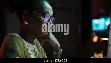 Portrait of Black Female Video Game Designer Creating Metaverse and Design Video Game Character in Creative Office at Night. Focused Woman Working on a New 3D Level on Her Desktop Computer Stock Photo
