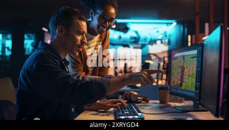 Portrait of Young Creative Director and Female Designer Talking About Work, Making Changes on Project. Two Stylish Diverse Employees Discussing Level Landscape on Computer in Game Development Company Stock Photo