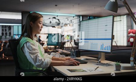 Female Asian Manager Working on Desktop Computer With Analytics Reporting Software on Display in Office. Stylish Woman Analyzing Financial Data Stock Photo