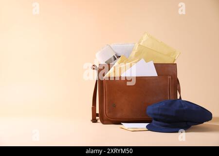 Brown postman's bag, envelopes, newspapers and hat on beige background. Space for text Stock Photo