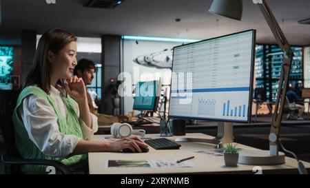 Female Asian Manager Working on Desktop Computer With Analytics Reporting Software on Display in Office. Stylish Woman Analyzing Financial Data Stock Photo