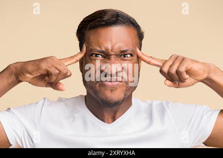 Black Man Concentrating Hard Pointing Fingers At Forehead In Studio Stock Photo