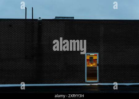 31DEC 2015, ONTARIO, CANADA - SIngle door at the back of a restaurant building with light coming from inside Stock Photo