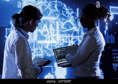 Trained programmers brainstorm ways to use AI cognitive computing to extract usable information from complex data. Adept employees implement artificial intelligence to process massive datasets Stock Photo