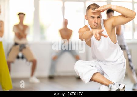 Young man together with group of teenage students, learn to dance hip hop in choreographic hall Stock Photo