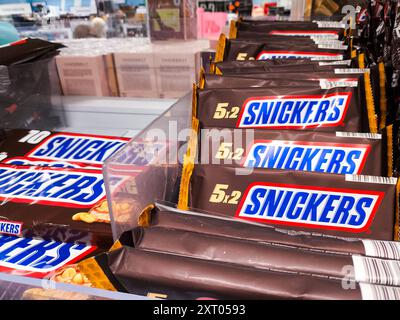 Bavaria, Germany - August 12, 2024: Snickers chocolate bars in family packs are presented on supermarket shelves *** Snickers Schokoriegel in Familienpackungen werden im Supermarktregal präsentiert Stock Photo