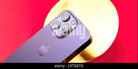 Paris, France - Sep 29, 2022: The latest Apple iPhone Pro is elegantly presented on a golden round support made of real gold, set against a rich red background, highlighting a design aesthetic that exudes luxury and sophistication Stock Photo