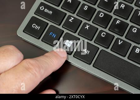 man pressing windows key on a laptop keyboard Stock Photo