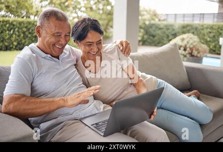 Senior couple, video call and laptop on home patio with greeting, internet and wave for online talk. Hug, relax and happy people together with website Stock Photo