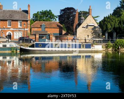 Saint Helen's Wharf is a noted beauty spot on the River Thames, just upstream of the medieval bridge at Abingdon-on-Thames. The wharf was for centuries an important transport and shipping link up the Thames and between canals from Oxford and the Midlands. Fine merchant houses rub shoulders with alms houses and the Saxon-era Saint Helens Church. Here we see pleasure and house boats moored alongside the Long Alley Alms Houses,  viewed on a fine mid-summer day from the north bank of the river. Stock Photo