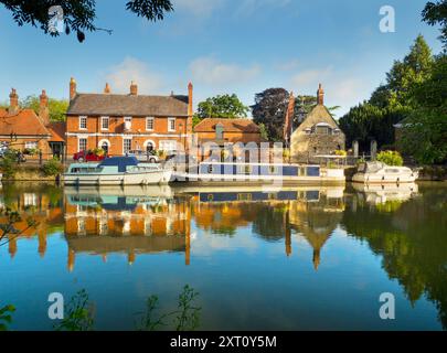 Saint Helen's Wharf is a noted beauty spot on the River Thames, just upstream of the medieval bridge at Abingdon-on-Thames. The wharf was for centuries an important transport and shipping link up the Thames and between canals from Oxford and the Midlands. Fine merchant houses rub shoulders with alms houses and the Saxon-era Saint Helens Church. Here we see pleasure and house boats moored alongside the Long Alley Alms Houses,  viewed on a fine mid-summer day from the north bank of the river. Stock Photo