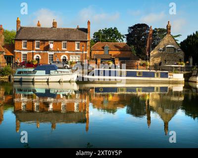 Saint Helen's Wharf is a noted beauty spot on the River Thames, just upstream of the medieval bridge at Abingdon-on-Thames. The wharf was for centuries an important transport and shipping link up the Thames and between canals from Oxford and the Midlands. Fine merchant houses rub shoulders with alms houses and the Saxon-era Saint Helens Church. Here we see pleasure and house boats moored alongside the Long Alley Alms Houses,  viewed on a fine mid-summer day from the north bank of the river. Stock Photo