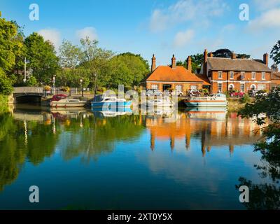 Saint Helen's Wharf is a noted beauty spot on the River Thames, just upstream of the medieval bridge at Abingdon-on-Thames. The wharf was for centuries an important transport and shipping link up the Thames and between canals from Oxford and the Midlands. Fine merchant houses rub shoulders with alms houses and the Saxon-era Saint Helens Church. Here we see pleasure and house boats moored alongside the Long Alley Alms Houses,  viewed on a fine mid-summer day from the north bank of the river. Stock Photo