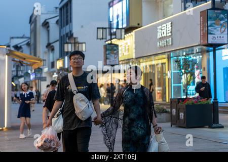 Suzhou, China - June 11, 2024 : A young couple walks hand-in-hand down a bustling street in Suzhou, China. Stock Photo