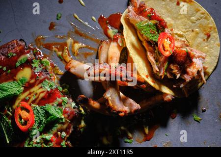 Top view of delicious rib tacos plated with herbs, hot peppers, and savory sauces. The ribs are cooked to perfection, paired with fresh mint and coria Stock Photo