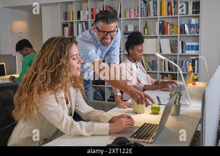 Male and female coworkers discussing project while working in office with diverse colleagues Stock Photo