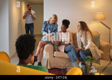 Group of multiracial coworkers sitting in cozy office lounge and having break during work Stock Photo