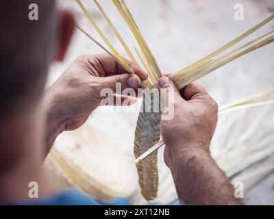 An expert artisan meticulously weaves a palmito basket, focusing on detailing as he intertwines the natural fibers Captured up close, this image highl Stock Photo