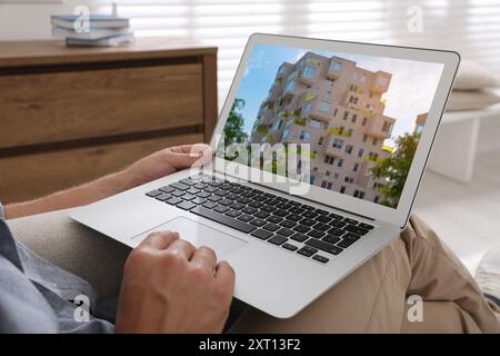 Man looking for house on real estate market website at home, closeup Stock Photo