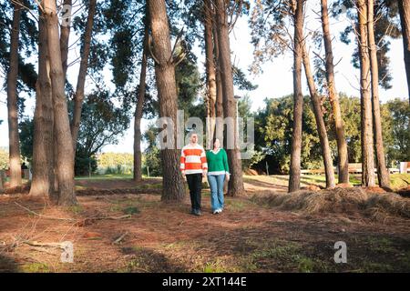 Young Latino couple holding hands in a serene forest setting during golden hour Stock Photo