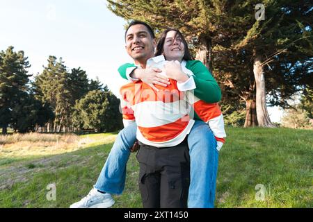 Young Latino couple smiling and having fun with a piggyback ride in a sunny park, known as Pareja 1 in the dataset Stock Photo