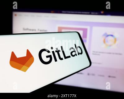 Mobile phone with logo of American open-source software company GitLab Inc. in front of business website. Focus on center-left of phone display. Stock Photo