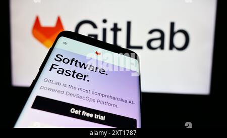 Smartphone with webpage of US open-source software company GitLab Inc. in front of business logo. Focus on top-left of phone display. Stock Photo