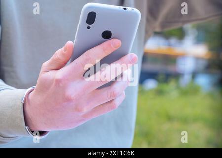 Unrecognizable man browsing the internet using mobile device outdoors. Stock Photo
