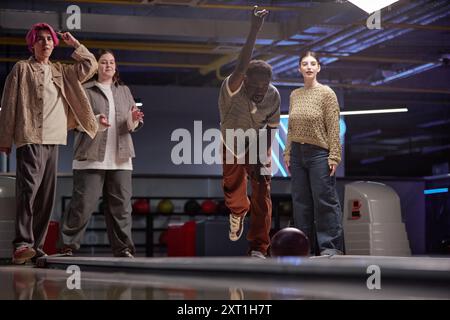 Group of friends enjoying bowling game together in recreational complex, mingling and sharing laughs while showing different emotions from joy to concentration Stock Photo