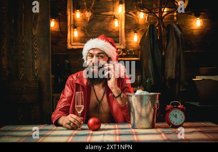 Happy Santa posing with phone. Modern santa claus in red clothes. Surprised Santa man using smart phone. Stock Photo
