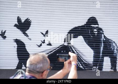 The new artwork unveiled by Banksy at London Zoo, depicting a gorilla lifting up a shutter at the entrance allowing a number of birds to escape, while the eyes of other animals can be seen lurking in the darkness, the ninth artwork in his animal-themed collection. Picture date: Tuesday August 13, 2024. Stock Photo