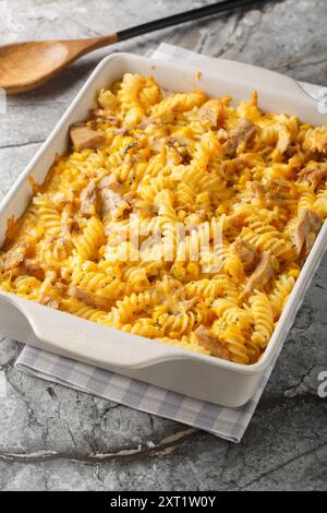 Tuna casserole pasta bake with a creamy sauce, sweet corn and crunchy topping, baked until golden closeup on the baking dish on the table. Vertical Stock Photo