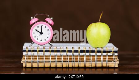 Alarm clock and apple on notebooks, education, knowledge or back to school banner Stock Photo