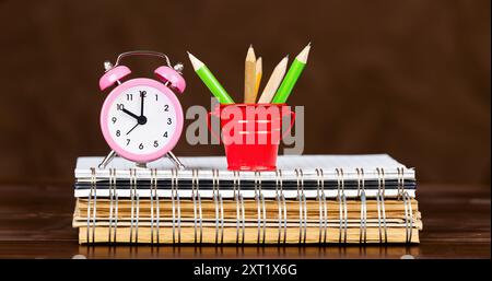 Alarm clock and pencils on notebooks, education, study or back to school background Stock Photo