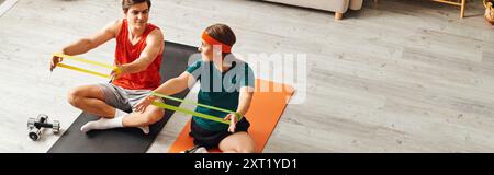 A woman with a prosthetic leg and her boyfriend work out together at home, using resistance bands. Stock Photo
