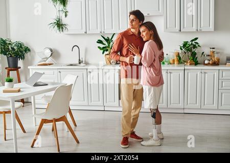 A couple embraces in a modern kitchen, enjoying a cup of coffee. Stock Photo