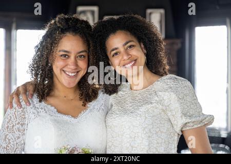 Two smiling women with curly hair embracing each other in a room with natural light. panc05813 Copyright: xConnectxImagesx Stock Photo