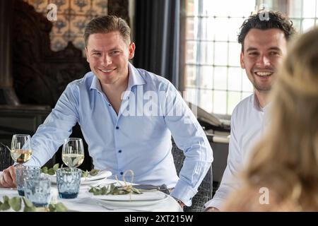 Two smiling men enjoying a meal with wine glasses at an elegantly set table, with a focus on the man in the foreground. panc05842 Copyright: xConnectx Stock Photo