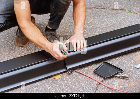 An aluminum rain gutter is bent using machine tool then cut to the required dimensions with shears Stock Photo