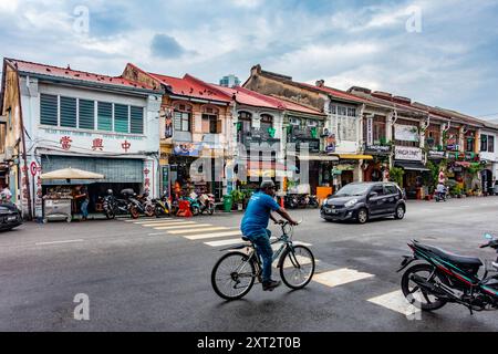 A busy street scene, a cyclist rides over a pedestrian crossing which  crosses Chulia Street in George Town, Penang, Malaysia Stock Photo