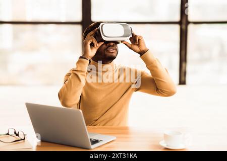 Afro businessman wearing augmented reality goggles at home Stock Photo